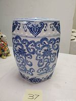 Front side view of the hexagonal porcelain garden stool showing detailed blue floral and scroll design on white background.