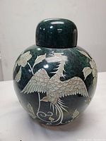Front view of a Chinese ginger jar showing etched birds and flowers on dark green mottled background.