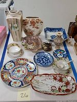 Wide view of Oriental porcelain vases and service ware displayed on table, showing variety of shapes and colors with floral designs.
