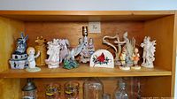 Shelf with vintage collectible figurines including blue windmill, Betsy Clark girl figurine, yellow ceramic container, hen figurine and figural lamp base