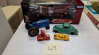 Overview of all five diecast vehicles including boxed 1934 Ford Pick Up Wrecker, tractor, and small Mickey Mouse vehicle