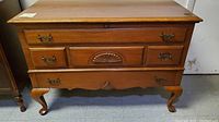 Front angled view of the vintage Lane cedar chest showing drawer details, brass handles, and carved decorative accents. Shows overall condition and spot on right corner.