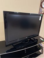 Front angled view of 42 inch LG flat screen TV on black stand with remote on stand surface