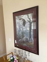 Framed art print hanging on a wall above glassware and flowers, showing full size and context.