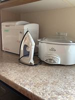 Photo of Sunbeam bread maker, Sunbeam steam iron, and Rival Crock-Pot slow cooker on countertop.
