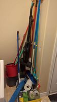 Various cleaning tools including vacuum, mops, and buckets arranged against a wall
