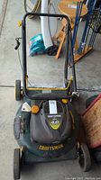 Front facing view of the green Craftsman lawn mower showing the engine cover with 4.0 HP sticker and yellow wheels.