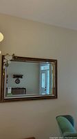 Full view of the large rectangular wall mirror with ornate frame and attached floral decoration.