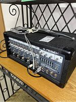 Side angle showing the Peavey XR 560 mixer with input cables connected on a shelf.