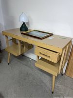 Front view of retro desk with Coleman camp light and framed photograph on top