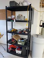 Black resin shelving unit in basement with items on shelves (contents not included in lot).