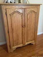 Front view of solid oak cabinet showing double doors with raised panels and round knobs