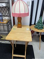 Photo of one wood folding TV tray with simple light wood finish and folding legs on black rug.