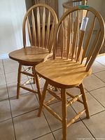Front view of two wood harped back swivel bar stools