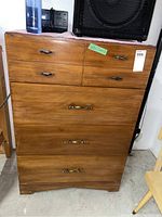 Front view of the medium brown wood dresser with metal handles, showing overall condition and drawer layout.