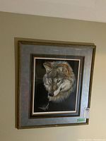 Framed artwork hanging on wall showing wolf head and butterfly artwork