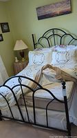 Full view of double bed with metal frame, mattress, pillows, and bedding.