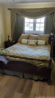 Full view of queen size bed with headboard and footboard in a bedroom, dressed with paisley bedding.