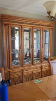 Front view of the wood and glass lighted hutch and buffet showing the glass doors, interior shelves, and two-piece design.