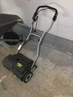 Full side view of the Yardworks electric dethatcher showing structure, handle, motor housing, and wheel.