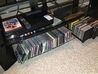Overall view showing the Samsung player, remote control, DVD movies on top, and collection of music CDs below.
