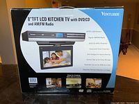 Front image of the product box showing product features and images of the compact LCD kitchen TV with DVD/CD player and AM/FM radio, including the screen size, design features, and functions.