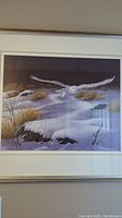 Framed art print showing a snow owl flying over snowy landscape with bushes and rocks, signed and numbered 61/450 by artist Rgis Vzina, titled 'Fantme'.