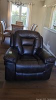 Front view showing dark brown faux leather upholstery, padded arms and back with contrast stitching in a residential interior.