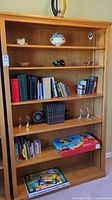 Front view of the wooden shelf filled with books, decorative items, and games to show shelf layout and condition