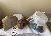 Two geodes and a plastic bag of glass beads displayed on a cloth surface, showing front and side views of the geodes.