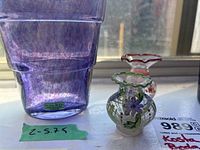 Photo of the purple Kosta Boda vase with front label and two small Abbott Collection miniature vases, placed in natural light on a windowsill.