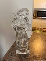 Front and side view of clear lead crystal angel figurine playing violin, standing on rectangular base, 8 inches tall.