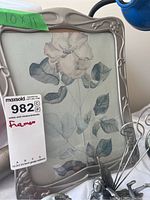 Front view of the large pewter photo frame showing decorative edges, 10x11 size label and botanical flower art inside.