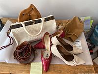 Overview of vintage shoes, belts, handbags laid on table including red and beige shoes, multiple belts, and handbags visible