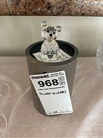 Swarovski crystal bear figurine on top of its original cylindrical box with label