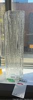 Full view of tall, rectangular clear crystal vase with vertical textured pattern standing on a windowsill.