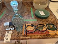 Photo of glass jug, art deco salt and pepper shakers, items on countertop alongside wine racks and bowls.
