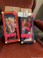 Two Barbie Collector dolls from the Dolls of the World series featuring Canada and United Kingdom in original boxes placed upright on a chair.