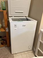 Front view of white Master Chef chest freezer with lid open and wire basket inside.