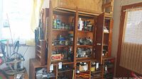 Wide view of wooden shelving holding various jars, bottles, and containers with numerous hardware items, tools, and supplies