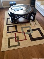 Overall photo of the area rug placed under a round coffee table with four stools, showing size and use context.