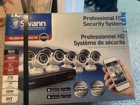 Front of the box showing 8 dome security cameras and DVR with a smartphone app example.