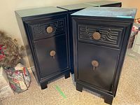 Two black side cabinets placed next to each other showing front view with drawer and door.