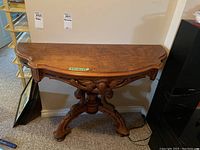 Front view of the vintage wooden table showing the carved apron and shape of the top.