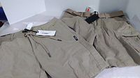 Two pairs of men's Silver Jeans Co khaki cargo Bermuda shorts side by side, new with tags, displayed on white background.