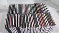 Top-down view of all 60 classic rock CDs tightly lined up showing spines with titles and artists with visible wear on plastic jewel cases.