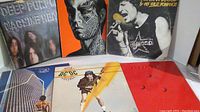 Photo showing six classic rock albums, including Deep Purple, AC/DC, and Todd Rundgren with colorful and artistic covers.