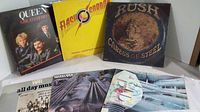 Photo showing six classic rock vinyl albums including Queen Greatest Hits III, Flash Gordon soundtrack, Rush Caress of Steel, and three other albums with various cover arts.