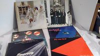 Six vinyl album covers laid out on a white surface showing varying cover art styles including photos and geometric designs.