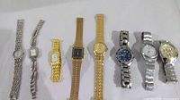 Photo showing 8 wristwatches aligned horizontally, including men's and ladies' styles with silver and gold-tone metal bands